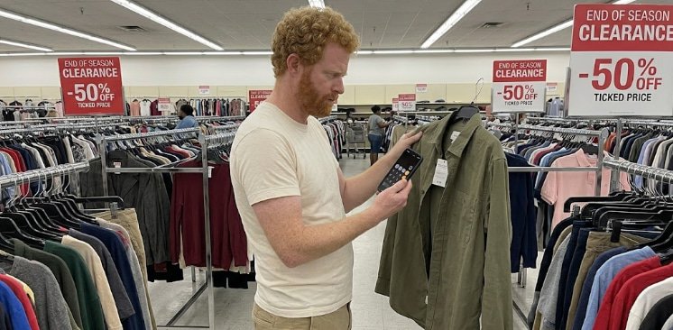 Man using phone calculator to decide jacket purchase in store