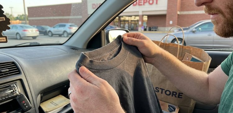 Man checking fabric weight of newly bought heavyweight tee in car