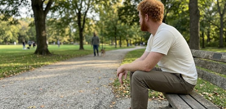 Well-fitting menswear what correct shoulder and hem break look like Man with correct fit sitting on park bench shoulder on bone clean break