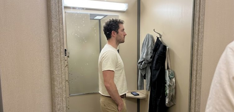 How to check t-shirt length fits right mid-fly rule side view Man checking t-shirt length side view in fitting room mirror hem at mid-fly