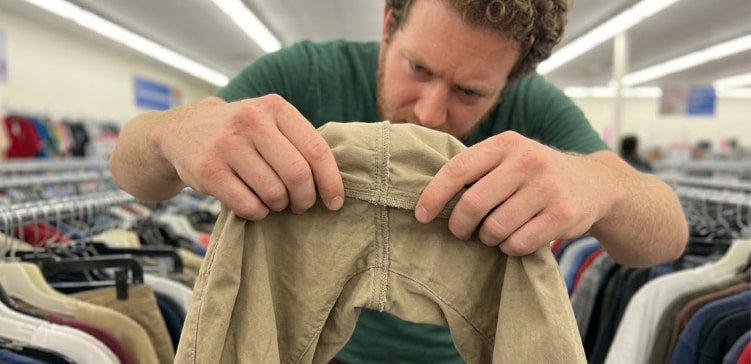 Man checking inside seam construction of budget chinos in store